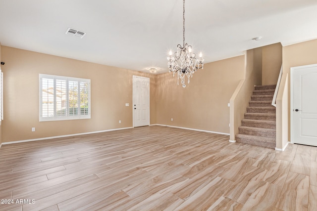 unfurnished living room featuring light wood-type flooring and an inviting chandelier