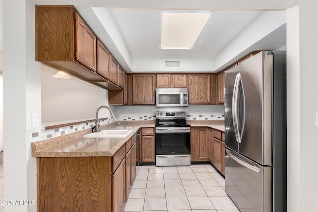 kitchen with light tile patterned floors, sink, light stone counters, and appliances with stainless steel finishes