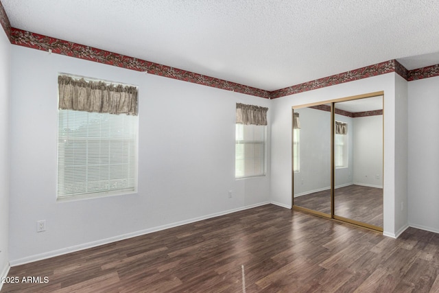 unfurnished bedroom with dark wood-type flooring, a closet, and a textured ceiling