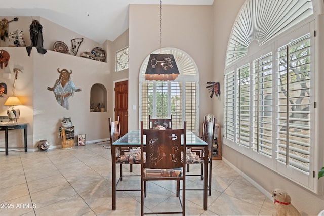 dining room featuring high vaulted ceiling, baseboards, and tile patterned floors