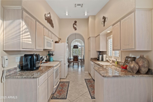 kitchen with light tile patterned flooring, white appliances, a high ceiling, a sink, and visible vents