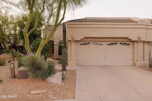 view of front of home with driveway, a tiled roof, an attached garage, and stucco siding