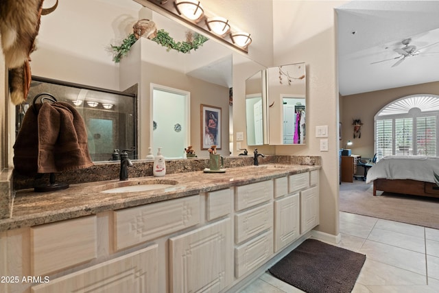 ensuite bathroom featuring double vanity, a stall shower, tile patterned flooring, and a sink