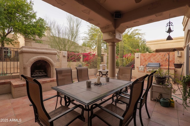 view of patio / terrace featuring outdoor dining space, an outdoor fireplace, and fence