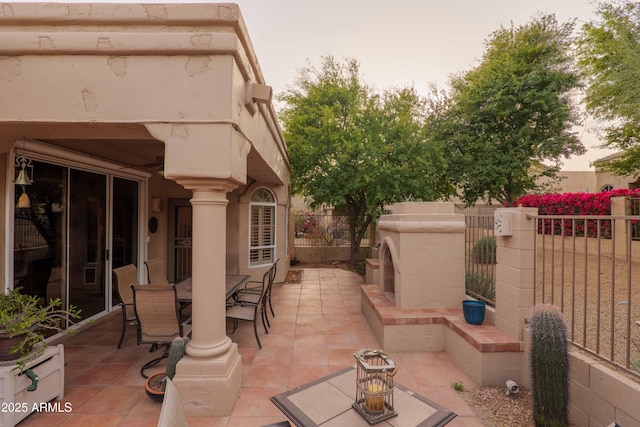 view of patio / terrace with fence, an outdoor fireplace, and outdoor dining space