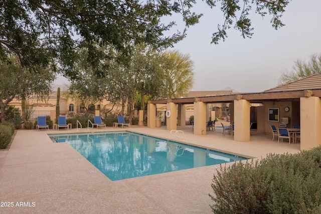 community pool with a patio area and fence