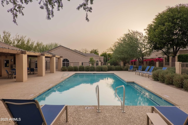 pool with a patio area and fence