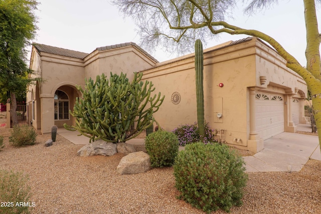 view of front facade with concrete driveway, a tile roof, an attached garage, and stucco siding