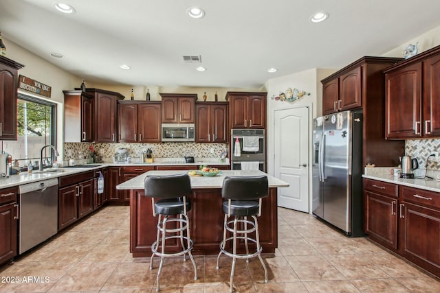 kitchen featuring sink, a breakfast bar area, a kitchen island, stainless steel appliances, and decorative backsplash