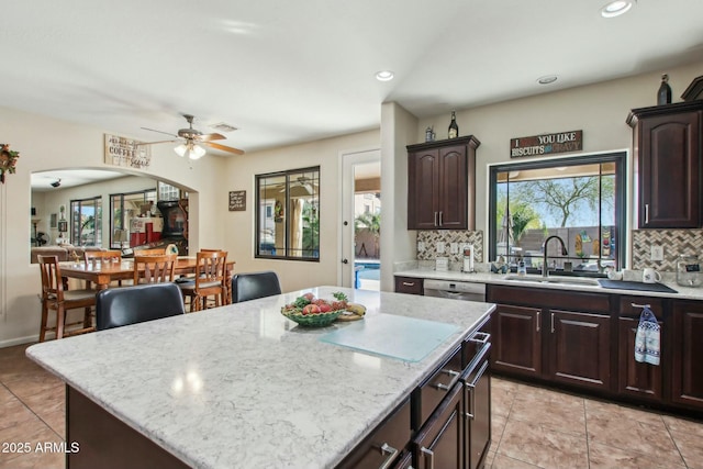 kitchen with light stone countertops, a center island, sink, and decorative backsplash