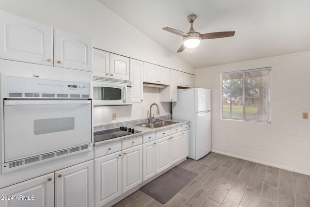 kitchen with lofted ceiling, sink, white cabinetry, white appliances, and dark hardwood / wood-style flooring