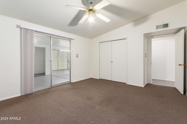 unfurnished bedroom featuring ceiling fan, brick wall, lofted ceiling, and dark carpet