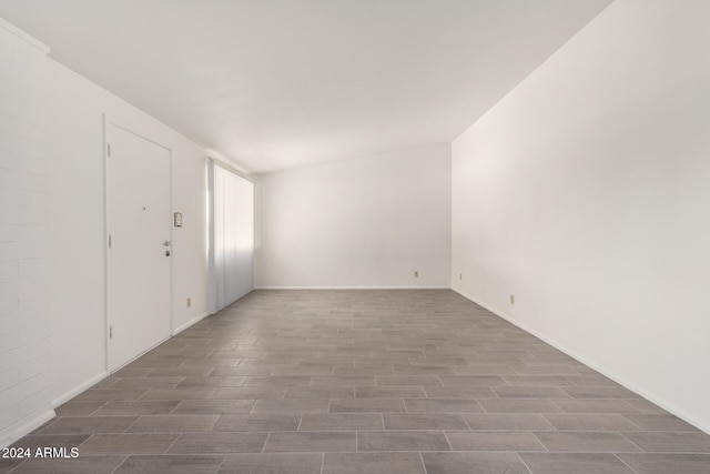 spare room with lofted ceiling and dark wood-type flooring