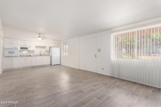 unfurnished living room with lofted ceiling, sink, light hardwood / wood-style flooring, and a healthy amount of sunlight