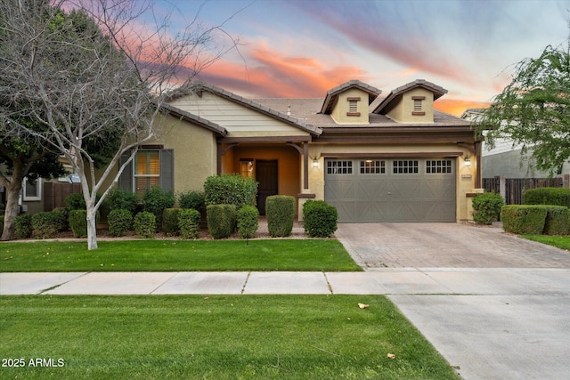 view of front of property featuring fence, a front yard, stucco siding, decorative driveway, and a garage