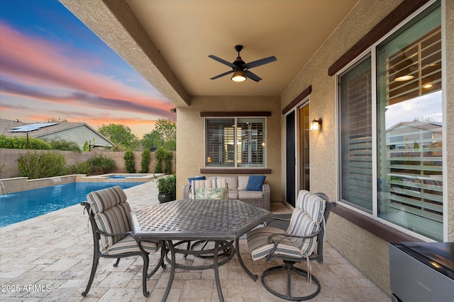 view of patio with a ceiling fan, fence, and a pool with connected hot tub