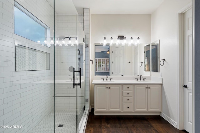 bathroom featuring double vanity, a stall shower, and a sink