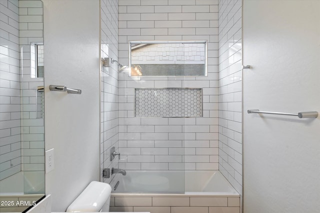 bathroom with toilet and tiled shower / bath