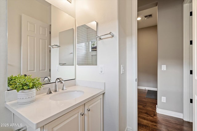 bathroom featuring visible vents, vanity, baseboards, and wood finished floors