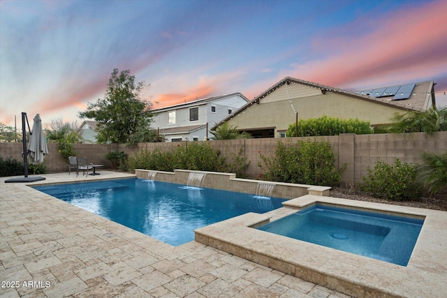 pool at dusk with an in ground hot tub, a patio area, a fenced in pool, and a fenced backyard