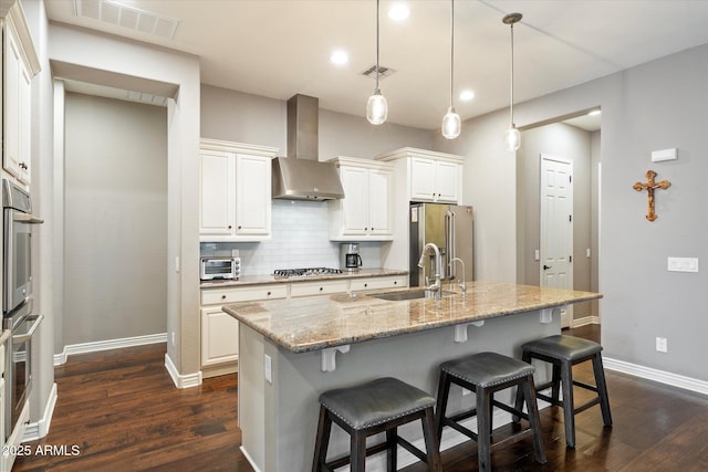 kitchen with visible vents, stainless steel appliances, wall chimney range hood, and decorative backsplash