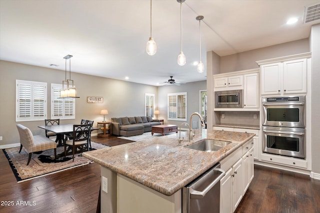 kitchen with a sink, stainless steel appliances, visible vents, and dark wood finished floors