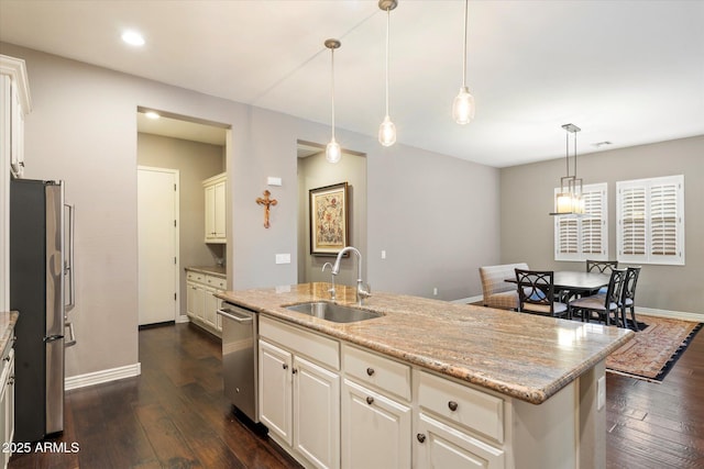 kitchen with a sink, baseboards, light stone counters, appliances with stainless steel finishes, and dark wood-style flooring