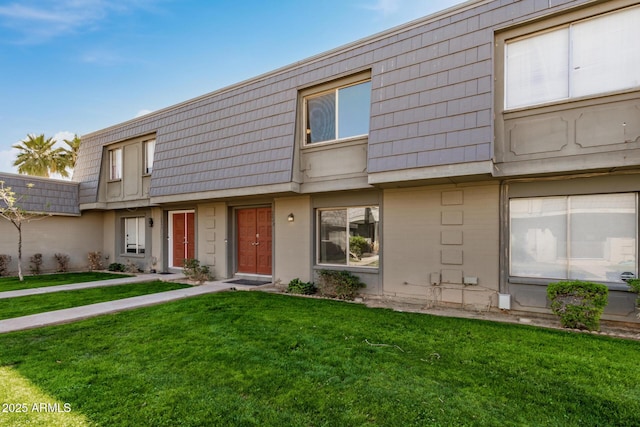 multi unit property with brick siding, a front lawn, and mansard roof