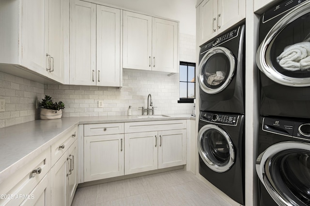 clothes washing area featuring sink, light tile patterned floors, cabinets, stacked washer and clothes dryer, and washer and dryer