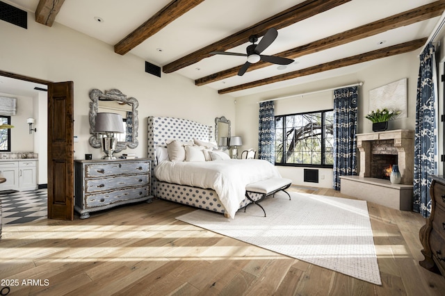 bedroom with ceiling fan, beam ceiling, and light hardwood / wood-style floors