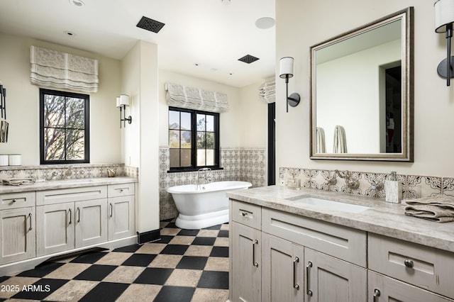 bathroom featuring tile walls, a tub to relax in, and vanity