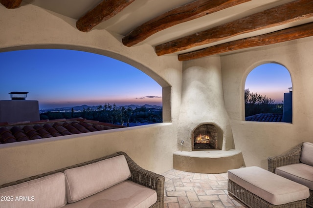 patio terrace at dusk with a mountain view and an outdoor fireplace