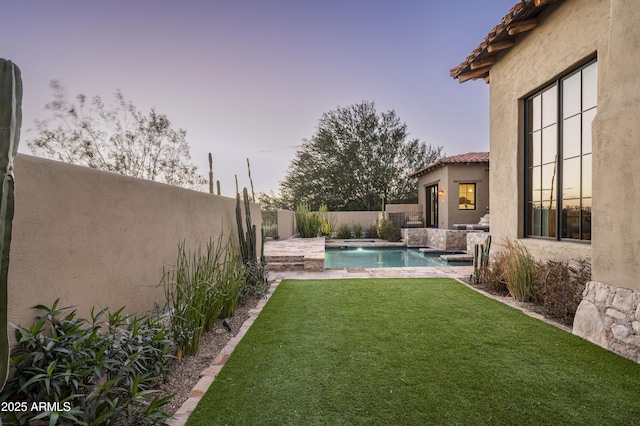 yard at dusk featuring a fenced in pool and pool water feature