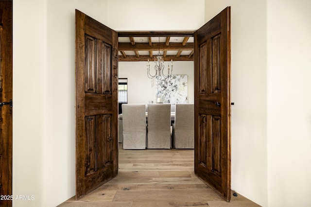 hallway featuring beam ceiling, a chandelier, and light wood-type flooring