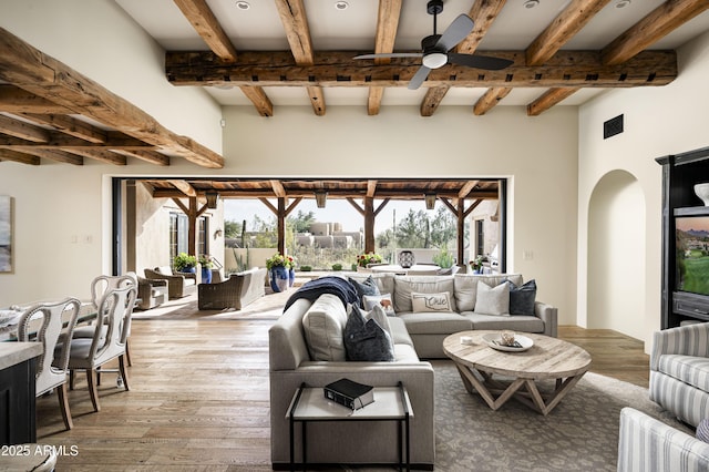 living room with beam ceiling, wood-type flooring, and ceiling fan