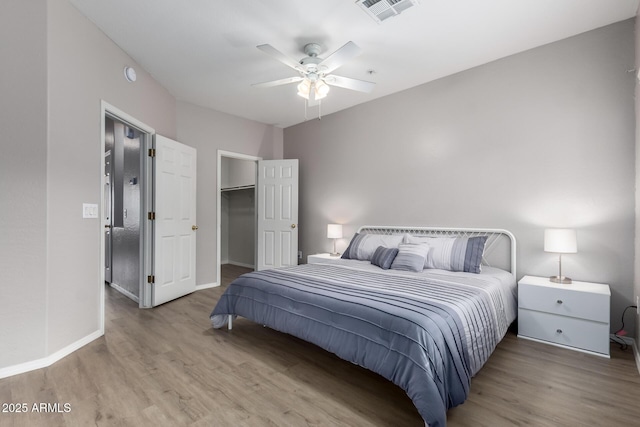 bedroom featuring ceiling fan, a walk in closet, and light hardwood / wood-style floors