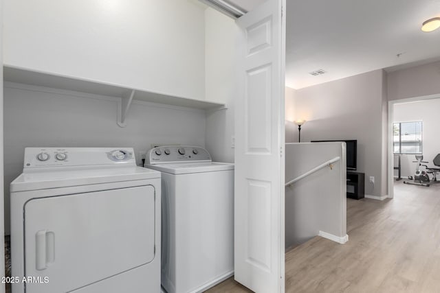 clothes washing area featuring light wood-type flooring and washer and clothes dryer