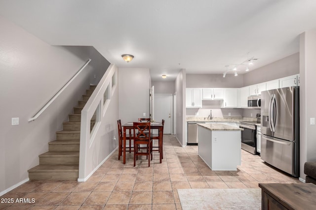 kitchen featuring sink, light tile patterned floors, a kitchen island, stainless steel appliances, and white cabinets