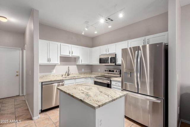 kitchen featuring sink, light stone counters, white cabinetry, appliances with stainless steel finishes, and a kitchen island