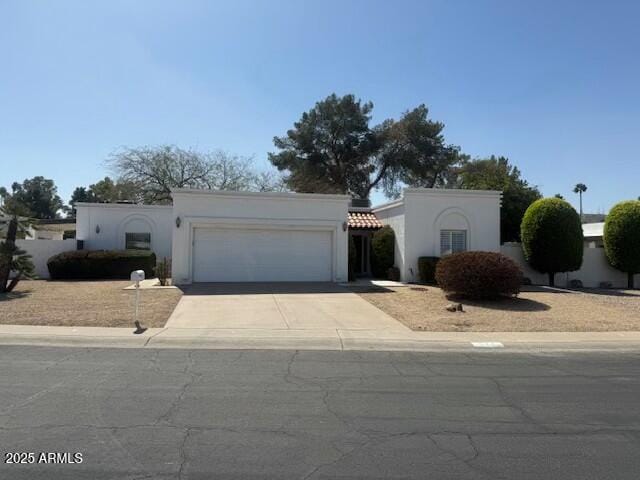 mediterranean / spanish-style house featuring a garage, a tiled roof, concrete driveway, and stucco siding