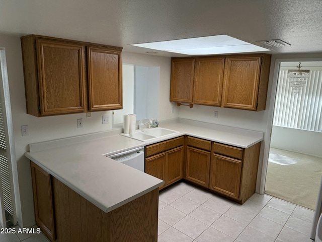 kitchen with brown cabinetry, light countertops, white dishwasher, and a sink