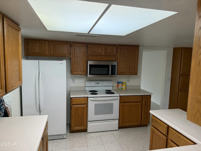 kitchen with light tile patterned floors, light countertops, white appliances, and brown cabinets