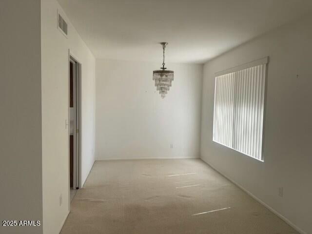 unfurnished dining area with light carpet, an inviting chandelier, and visible vents