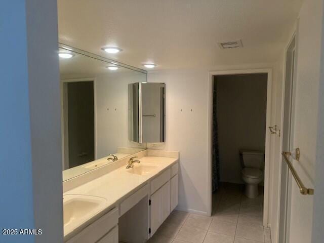 bathroom featuring tile patterned flooring, a sink, toilet, and double vanity