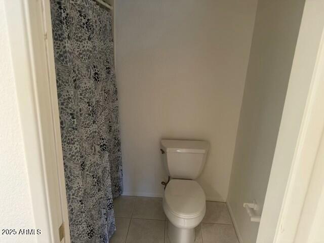 bathroom with tile patterned flooring, a shower with shower curtain, and toilet