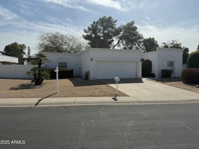 view of front of property with driveway, fence, an attached garage, and stucco siding