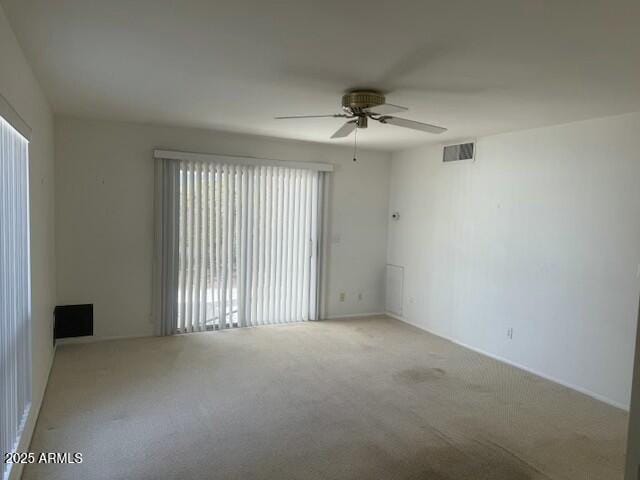 carpeted spare room featuring visible vents and a ceiling fan