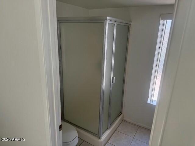 bathroom featuring a stall shower, toilet, and tile patterned floors