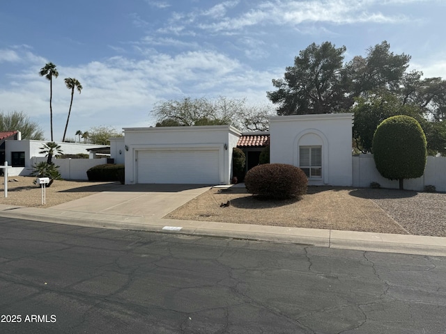 view of front of property featuring a garage, driveway, fence, and stucco siding