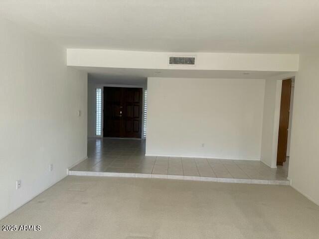 carpeted spare room with tile patterned flooring and visible vents